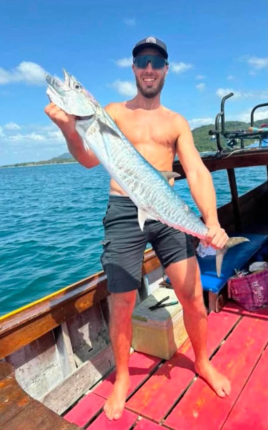 A guest holding a king mackerel caught from the boat off Koh Lanta