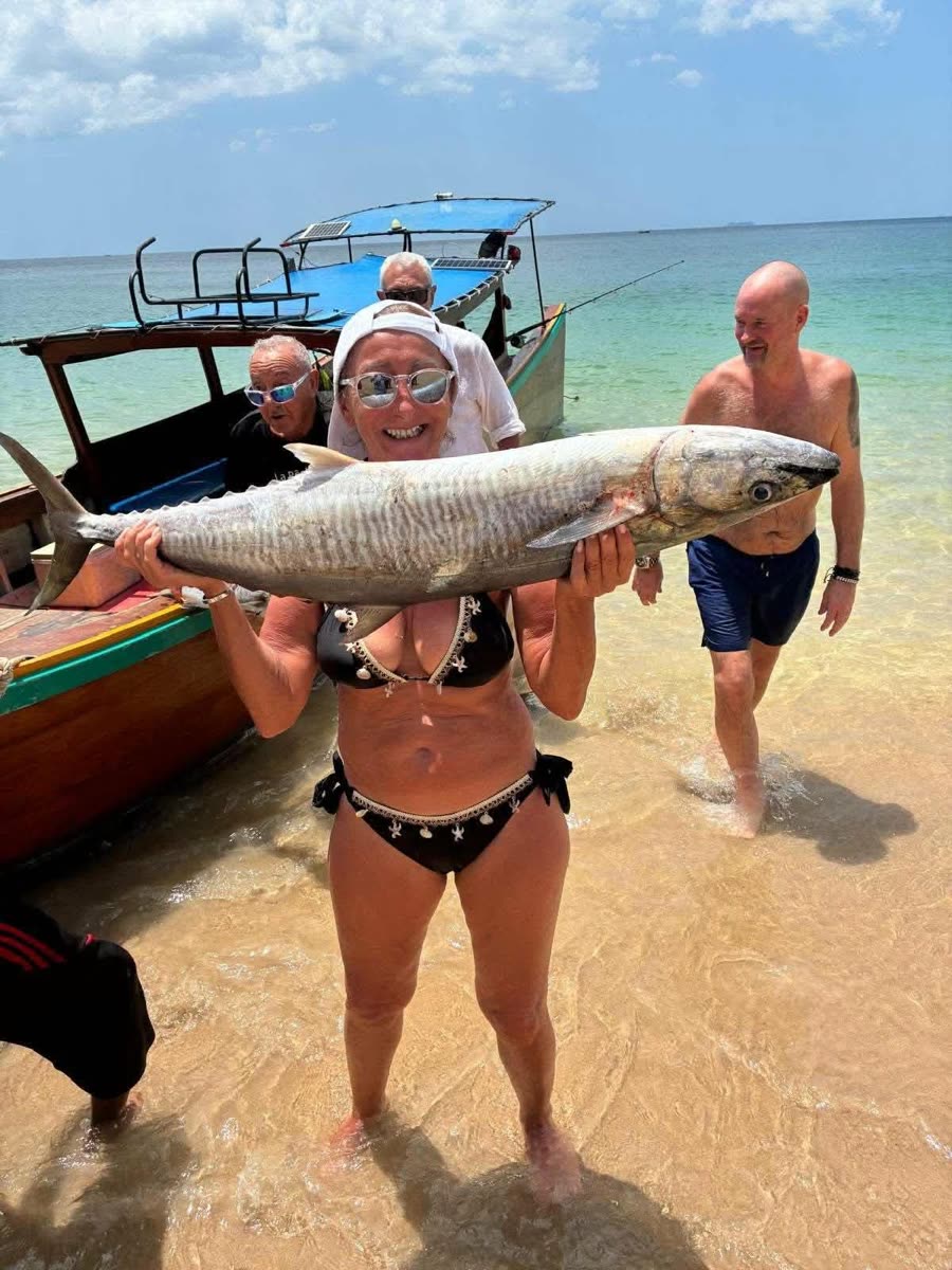 Guests carrying a large king mackerel ashore on a Koh Lanta beach